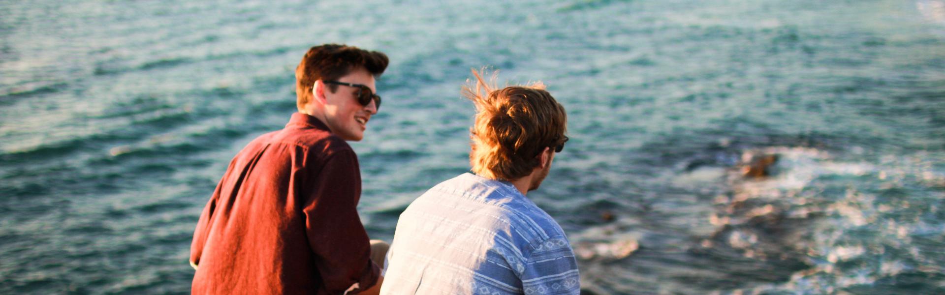 Two men talking while sitting at the beach.