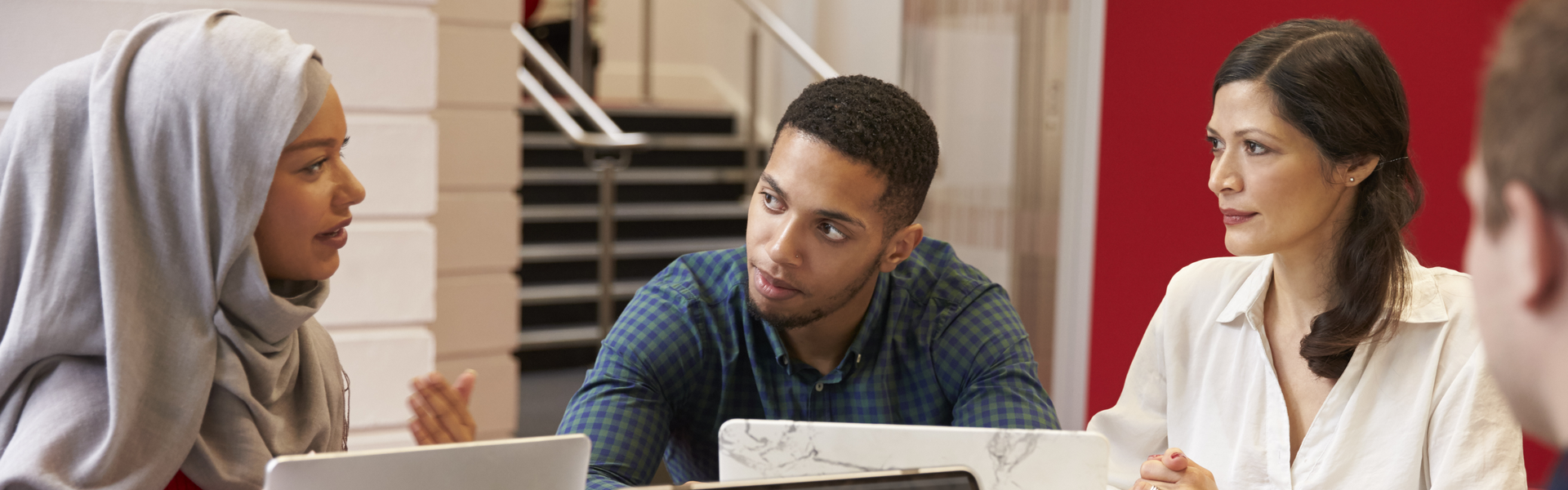 A group of ethnically-diverse students talking at a table.