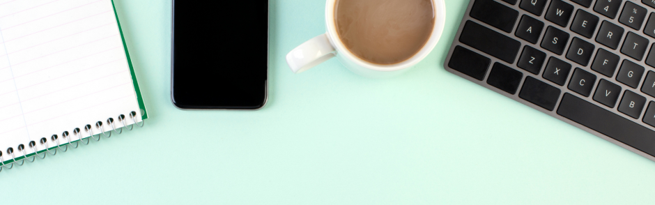 Mint green surface with keyboard, coffee, smartphone and notebook