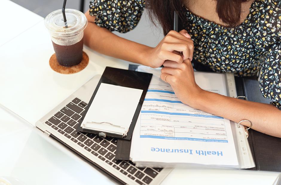 Closeup workspace of insurance broker, laptop, health insurance information form on desk