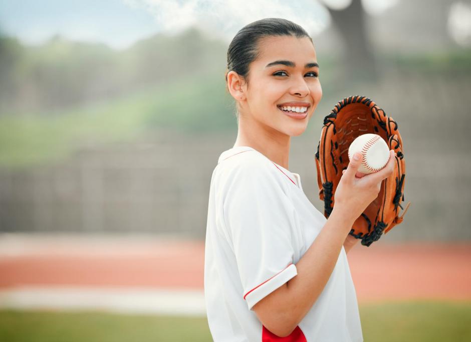 young woman smiling preparing to pitch (softball)