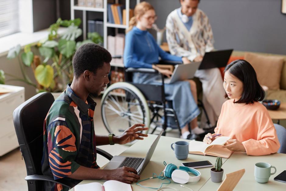 Colorful portrait of two young professionals talking while collaborating on project at meeting table