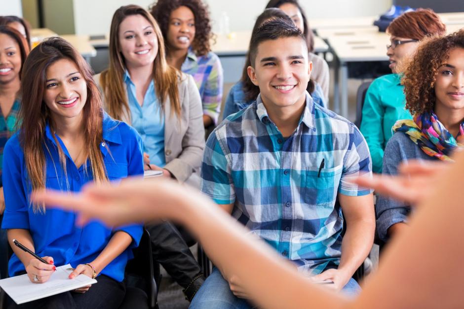 Diverse group of Hispanic, African American and Caucasian high school or college students are sitting in rows in lecture hall.