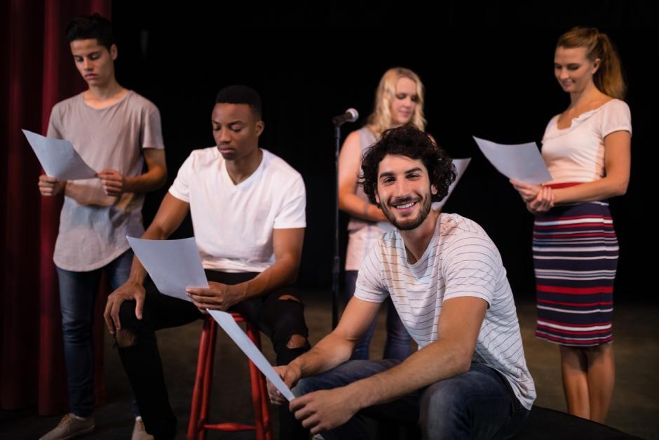 Actors reading their scripts on stage in theatre