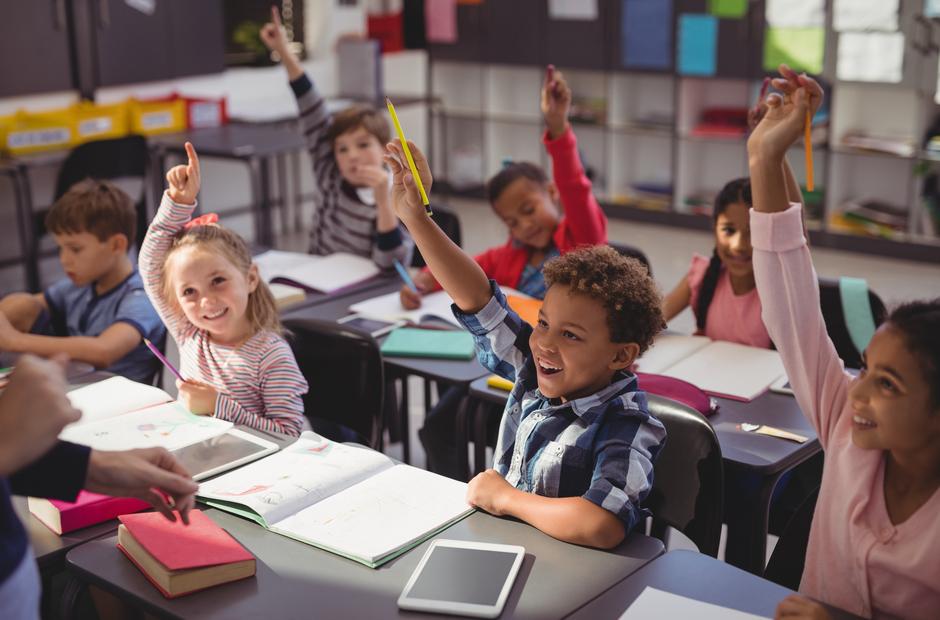 Kids raising their hands in class.