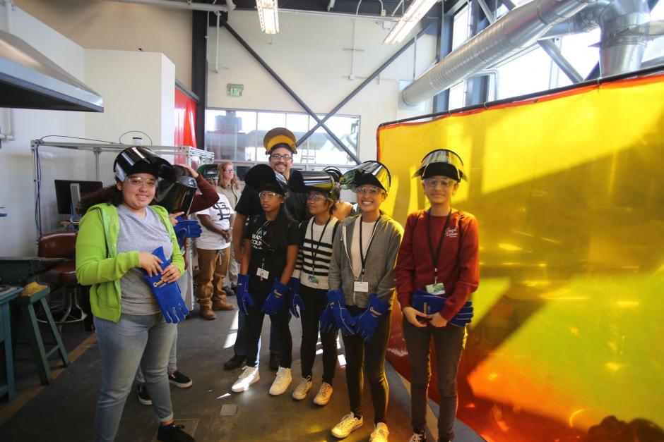 A group of female high school students working in a welding workshop.