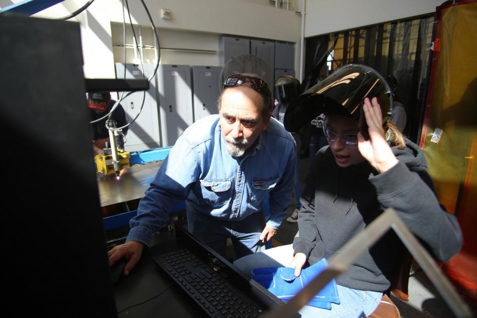 Sheet Metal Instructor, Time Shoemaker helps high school students calibrate computers for metal fabrication.