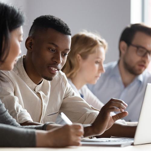 Multiethnic colleagues seated in conference room discuss new corporate app