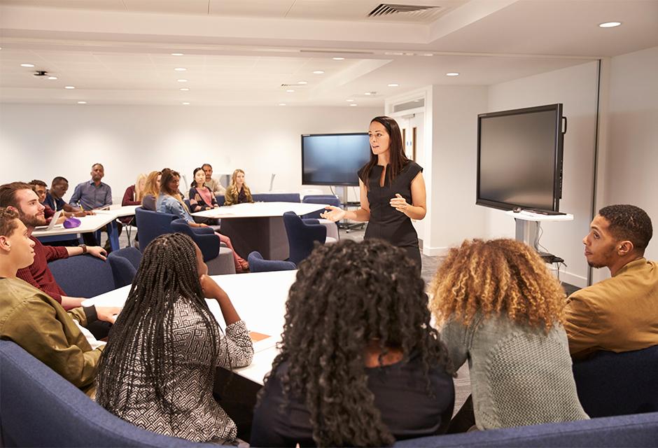 Female teacher addressing university students in a classroom