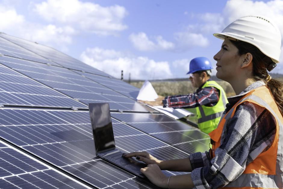 Two technicians in distance discussing between long rows of photovoltaic panels. Solar panel installer installing solar panels with a big copy space