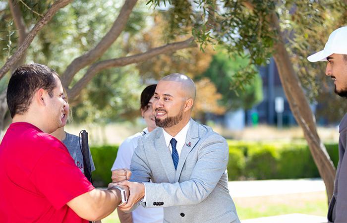 dr. Muñoz interacts with student on campus (shaking hands with a student with disability)