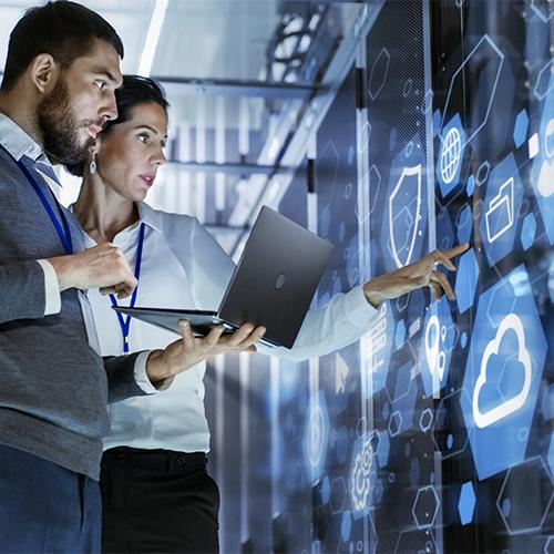 Male IT Specialist Holds Laptop and Discusses Work with Female Server Technician. They're Standing in Data Center, Rack Server Cabinet with Cloud Server Icon and Visualization. 