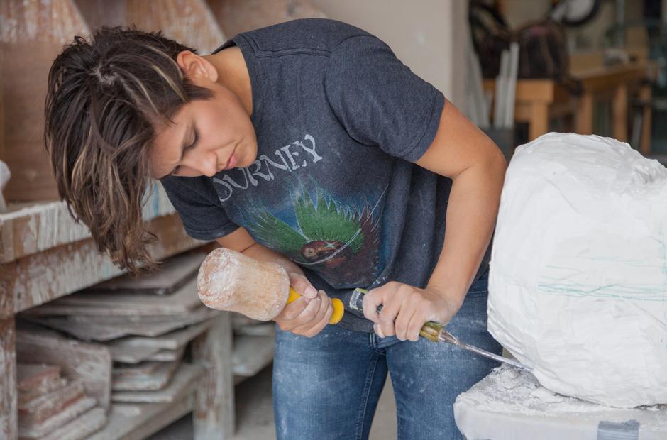 A student carefully chisels plaster for a project.